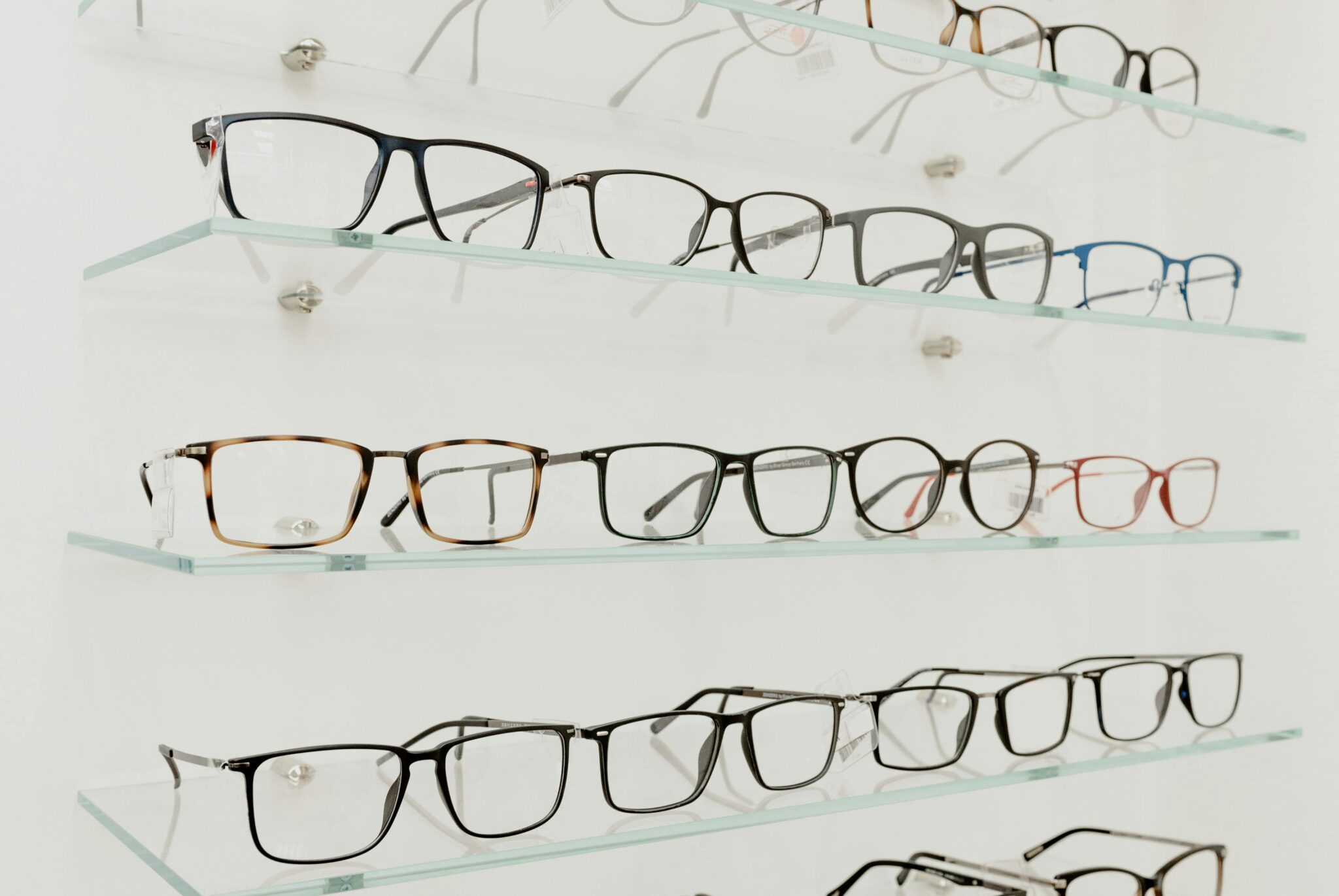 Variety of stylish eyeglasses for eyesight placed on glass shelves in optical shop